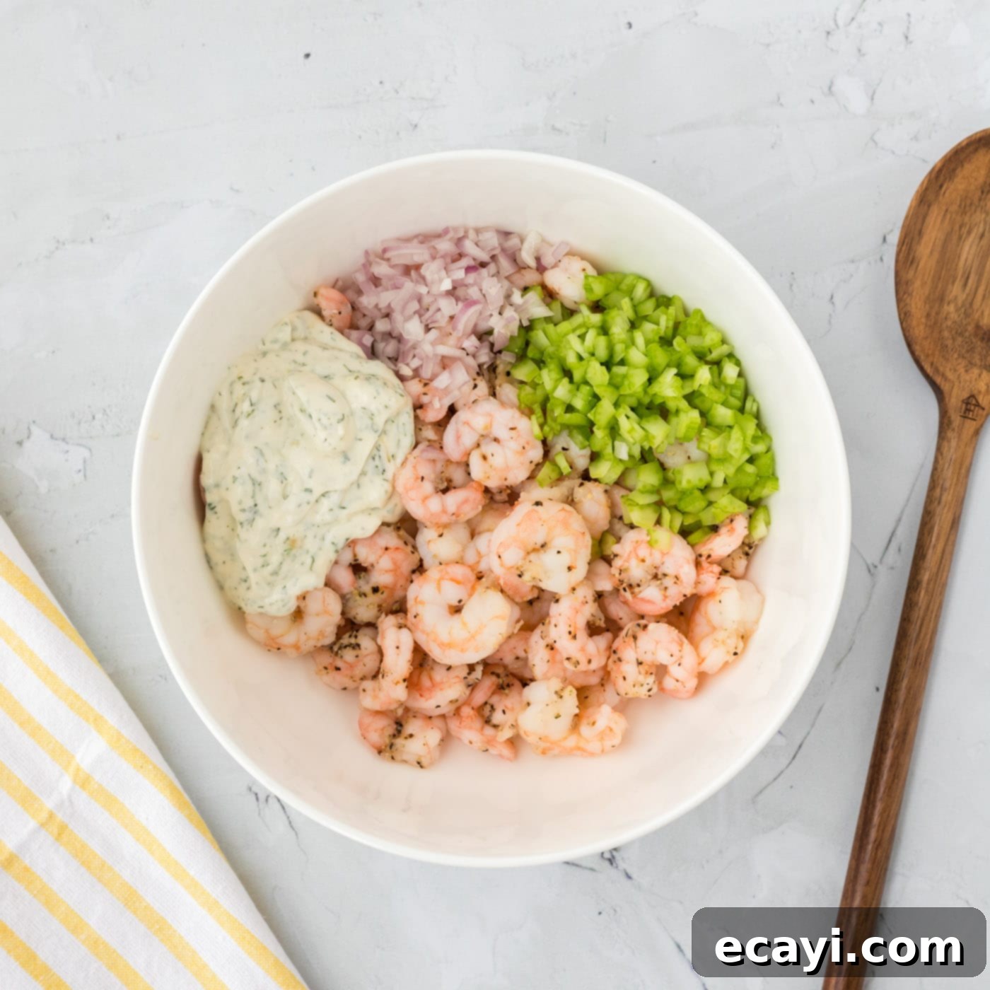 Zesty Shrimp Salad 7 shrimp salad ingredients being mixed in a large bowl with creamy dressing and fresh vegetables