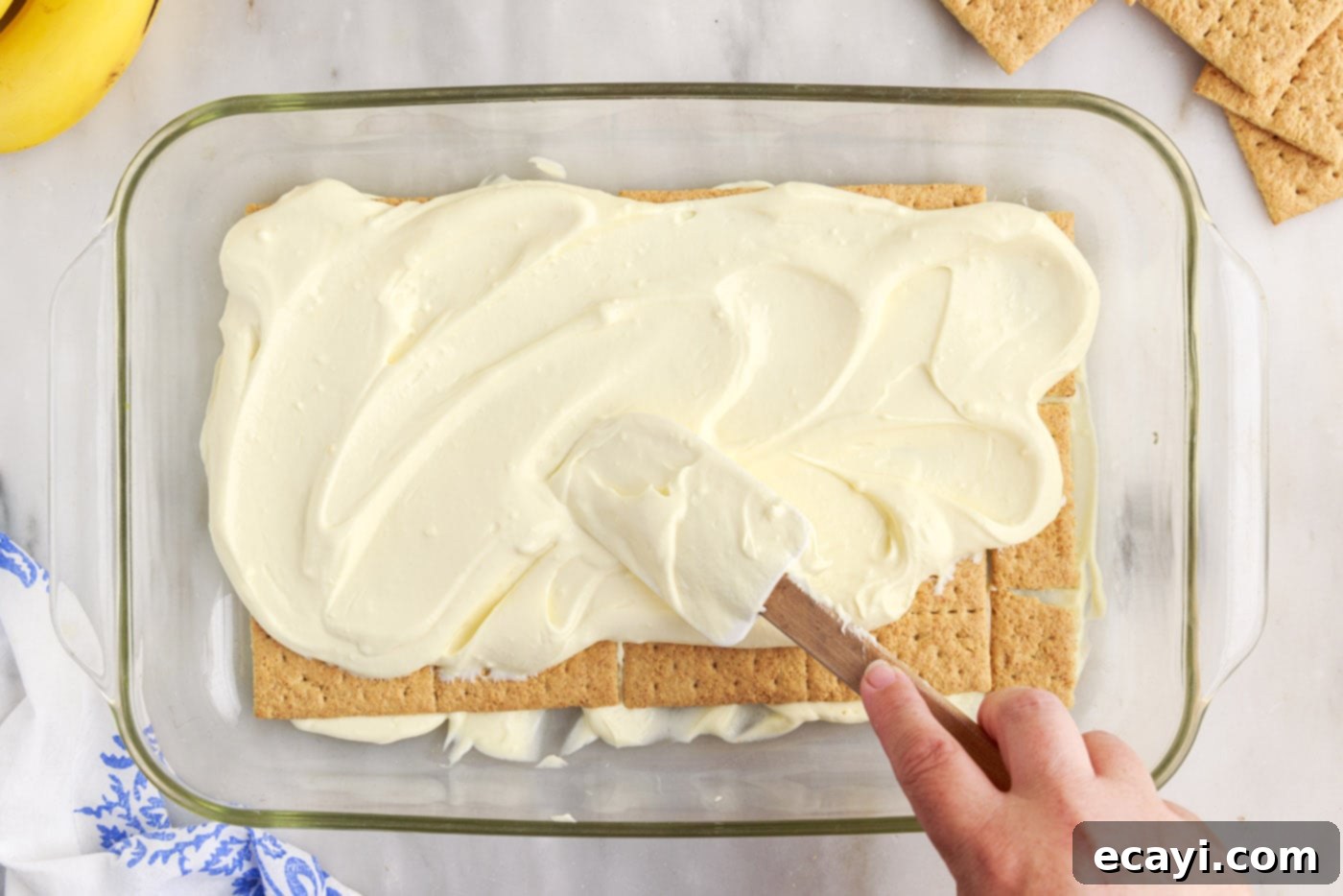 No-Bake Banana Cream Delight 11 spreading banana cream pudding on top of graham crackers