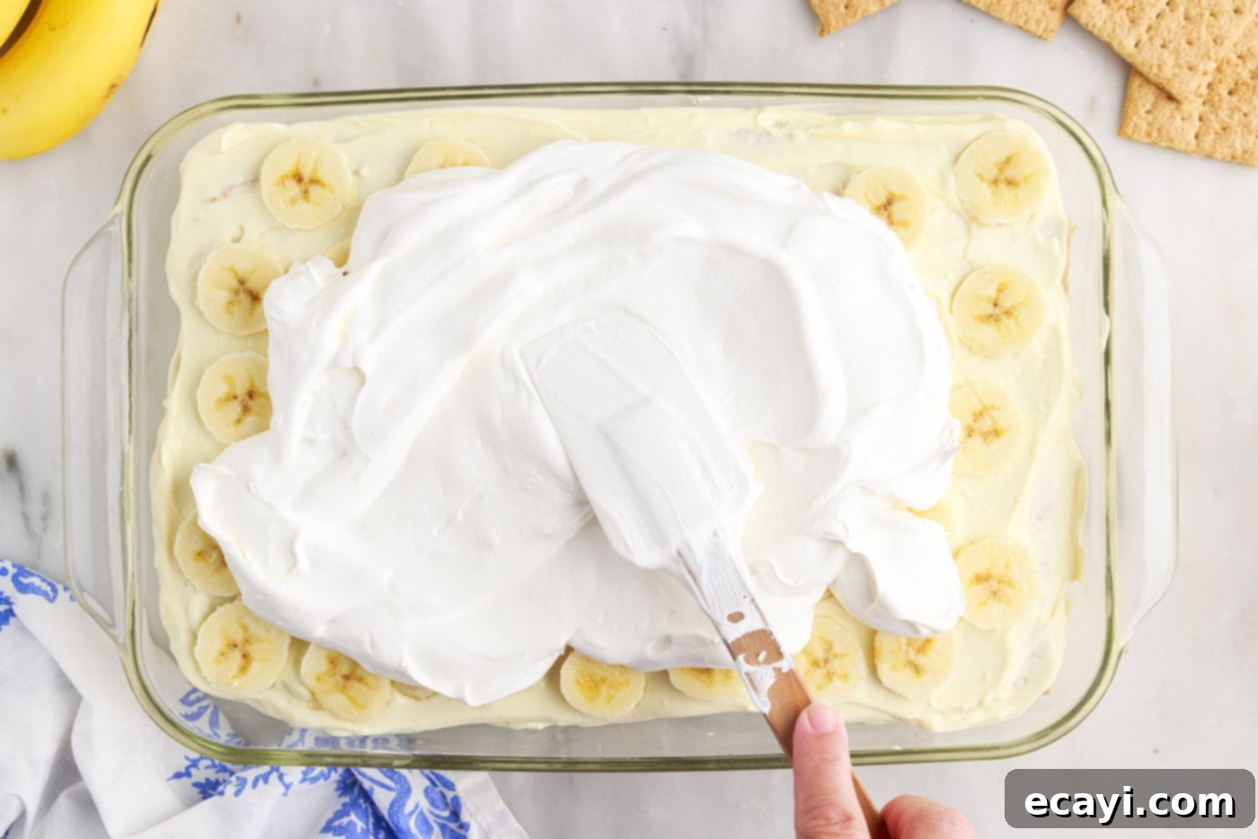 No-Bake Banana Cream Delight 13 spreading cool whip over the top of banana cream pie icebox cake