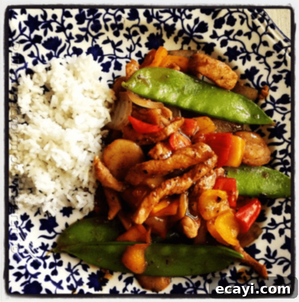 Peppered Pork Stir Fry with Sweet Peppers - AmandasCookin.com An overhead photo of a plate of peppered pork stir fry with sweet peppers with rice on the side.