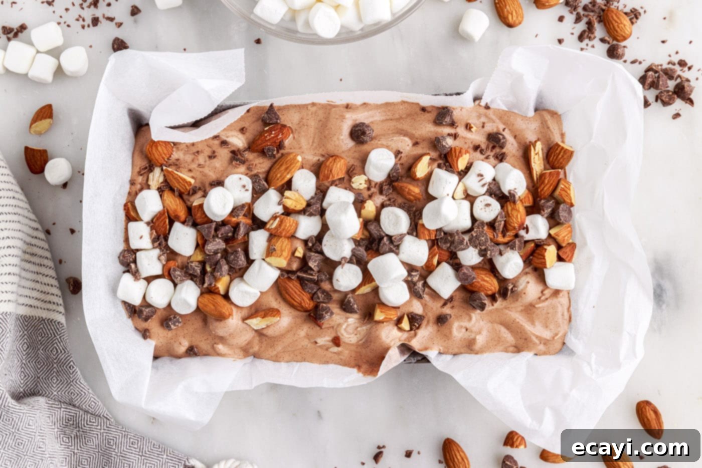 The Ultimate Rocky Road 12 no-churn rocky road ice cream in a pan, topped with chocolate chips, almonds, and marshmallows