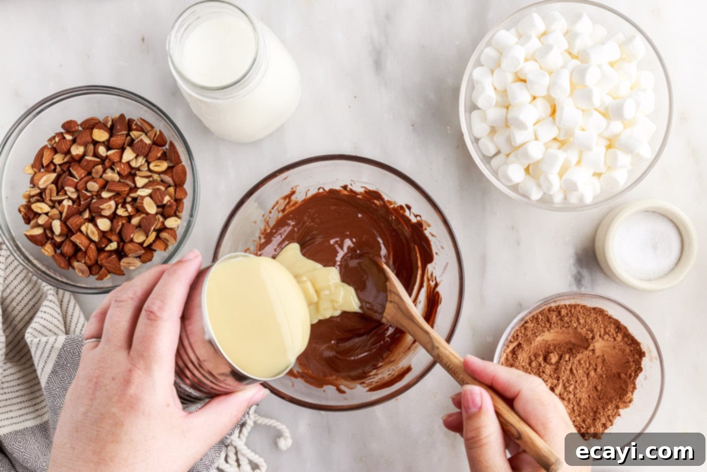 The Ultimate Rocky Road 6 stirring sweetened condensed milk into melted chocolate, creating a rich chocolate mixture
