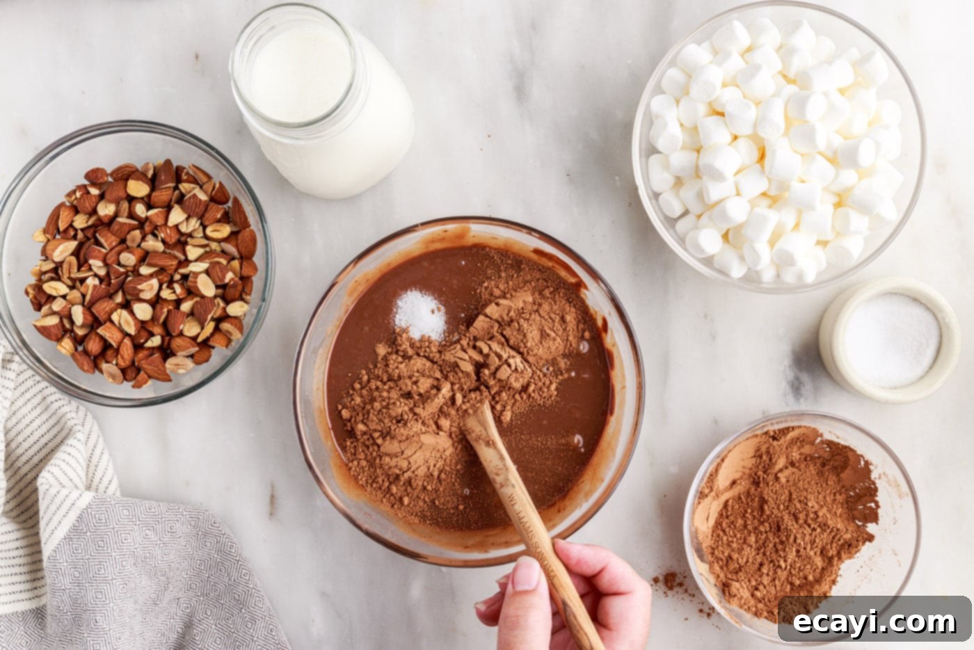The Ultimate Rocky Road 7 stirring chocolate ice cream base in a bowl with sea salt, vanilla, and cocoa powder
