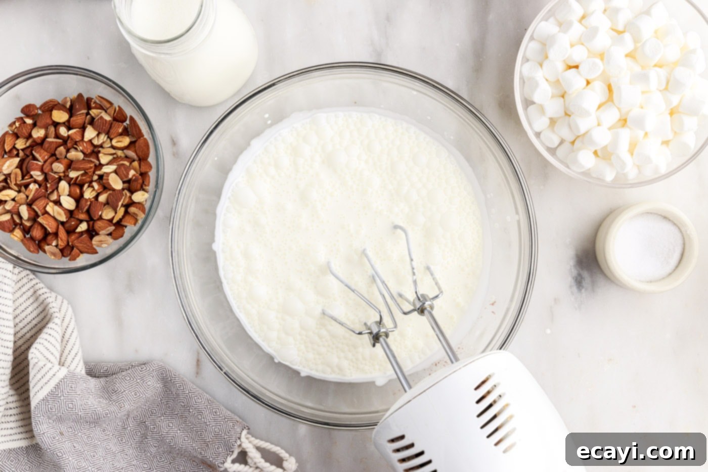The Ultimate Rocky Road 8 hand mixer whipping heavy cream in a bowl until stiff peaks are formed