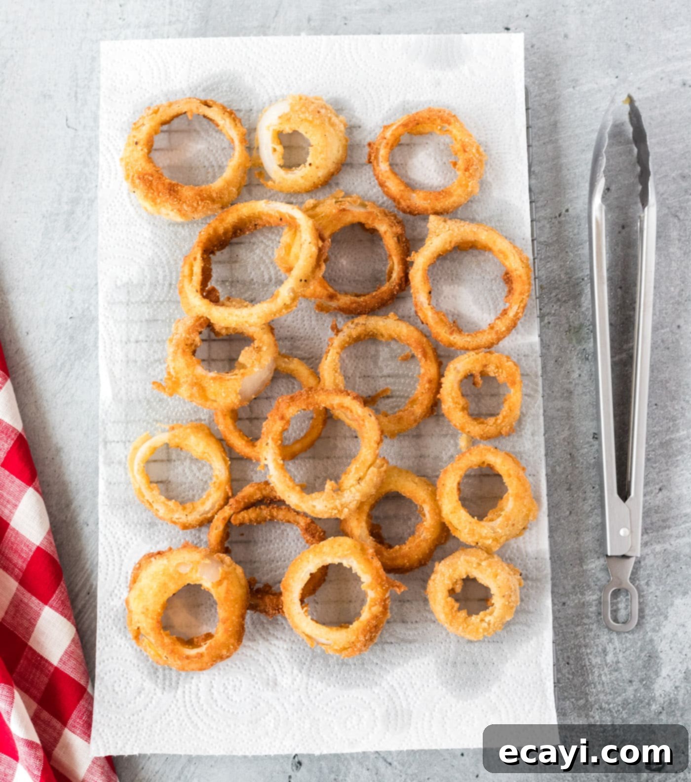 Golden Onion Crisps 11 Freshly fried onion rings draining on paper towels on a plate