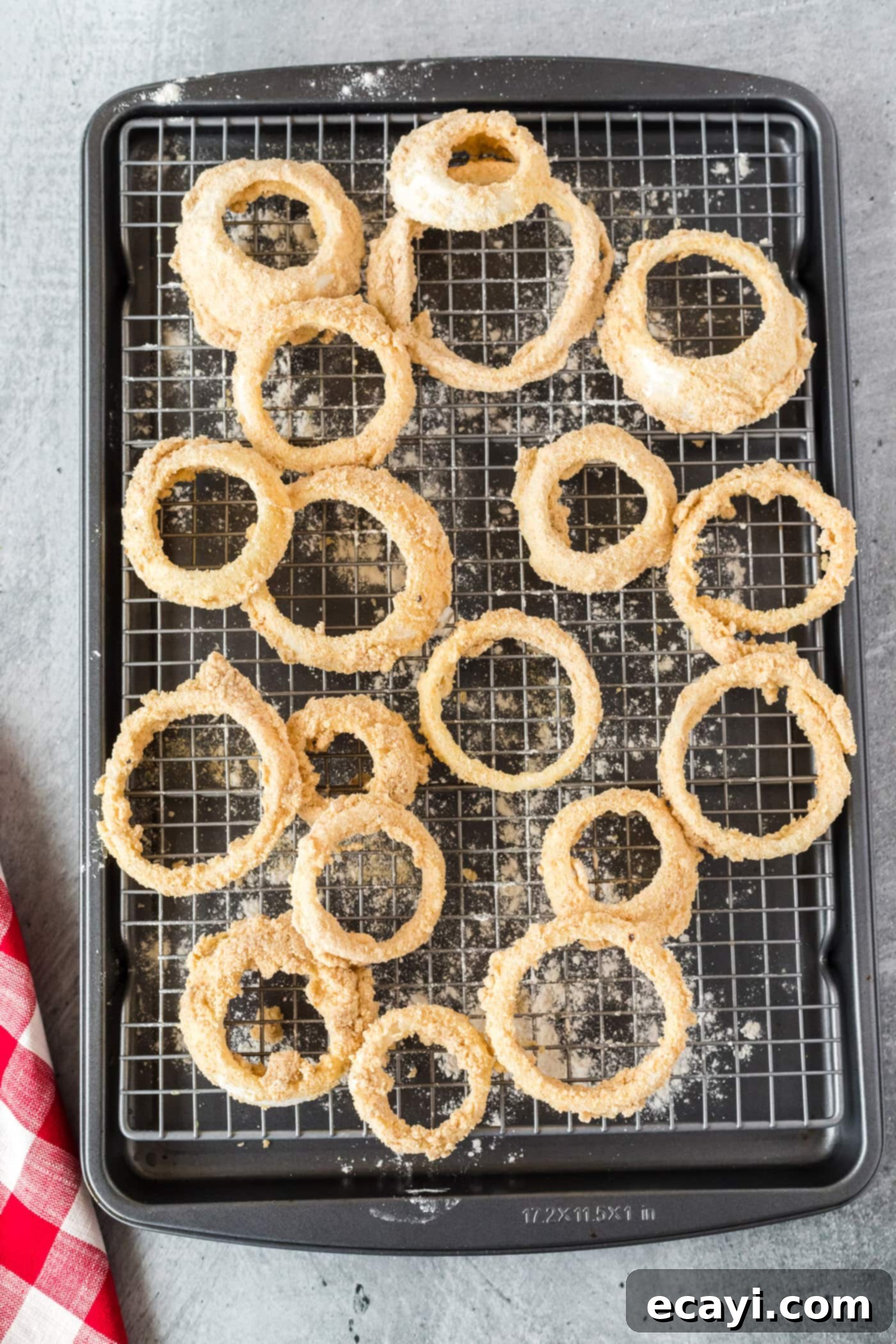 Golden Onion Crisps 9 Breaded onion rings neatly arranged on a baking sheet with a wire rack