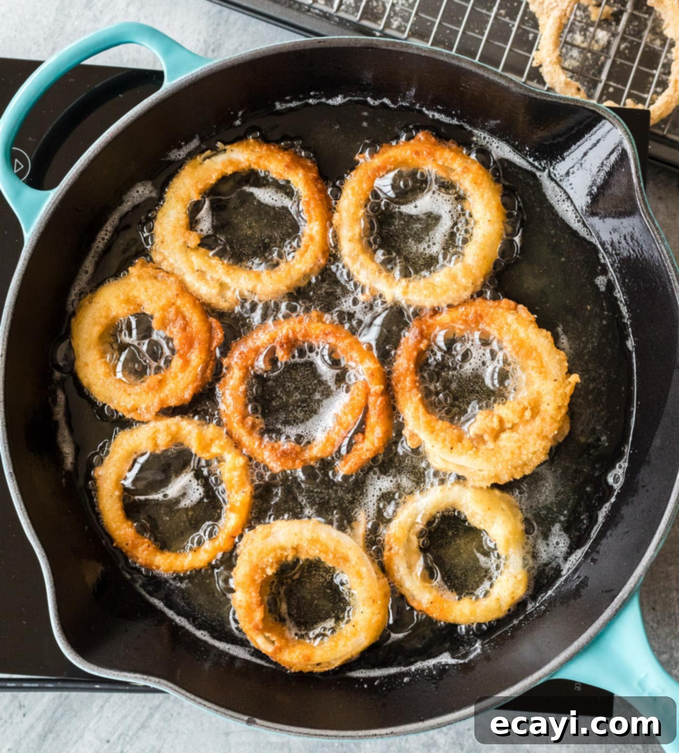 Golden Onion Crisps 10 Onion rings deep-frying in a skillet, bubbling and turning golden brown