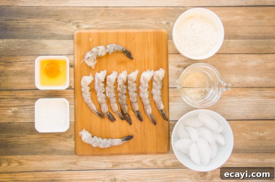 Golden Crispy Shrimp 4 A simple layout of fresh ingredients for crispy shrimp: raw shrimp, cornstarch, an egg, all-purpose flour, and a bowl of iced water.
