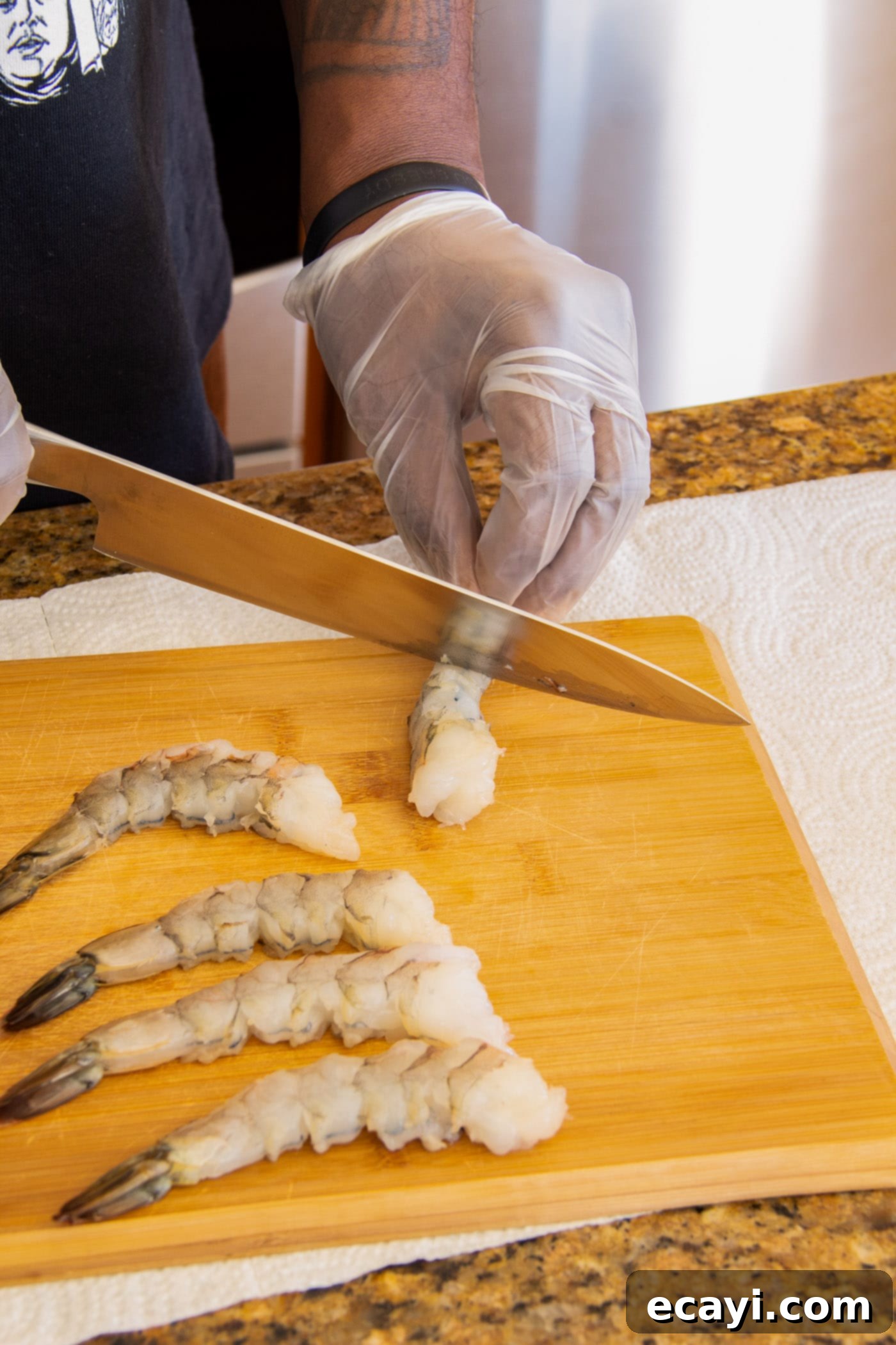 Golden Crispy Shrimp 5 A chef scoring fresh raw shrimp with a knife on a cutting board to prevent curling during the frying process.