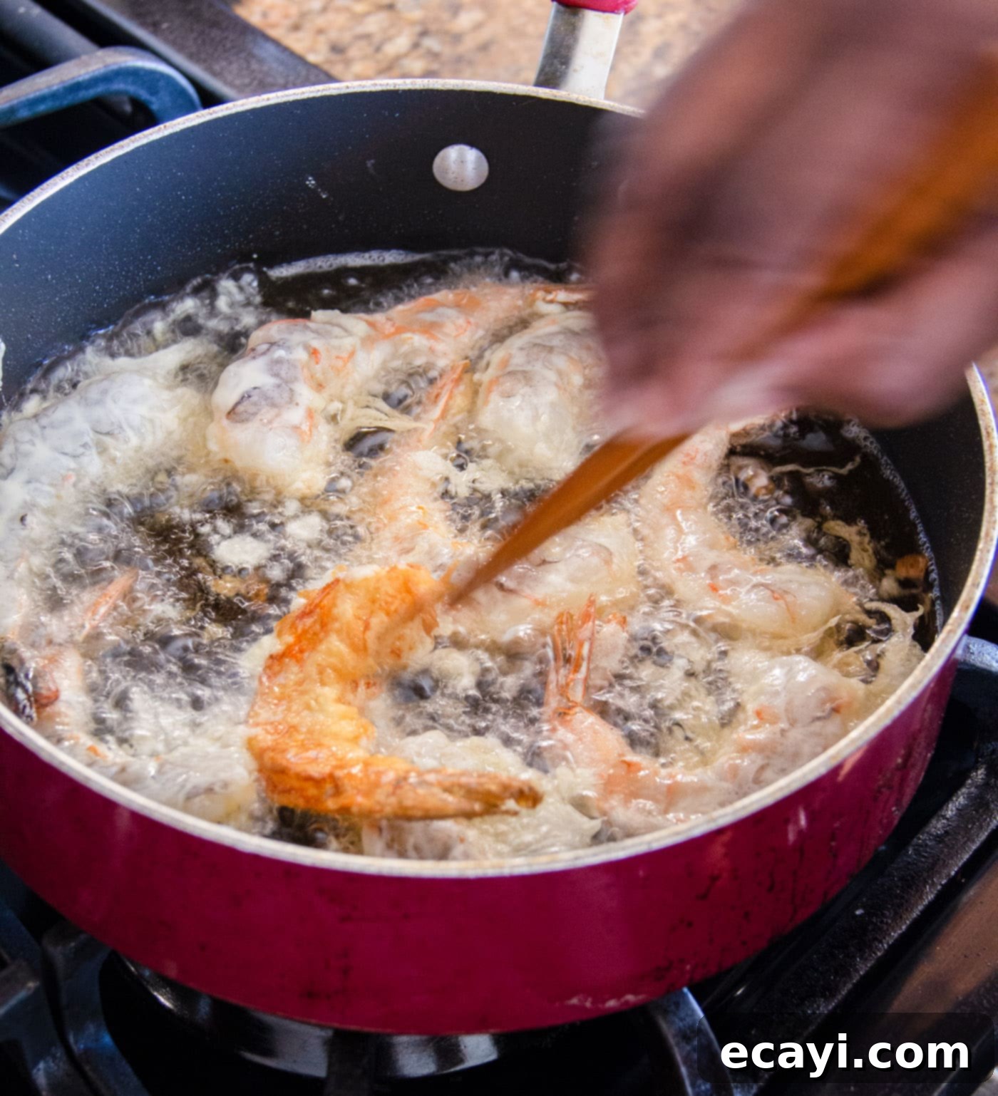 Golden Crispy Shrimp 10 Turning crispy fried shrimp in hot oil with tongs to ensure even cooking and a uniform golden crisp on both sides.