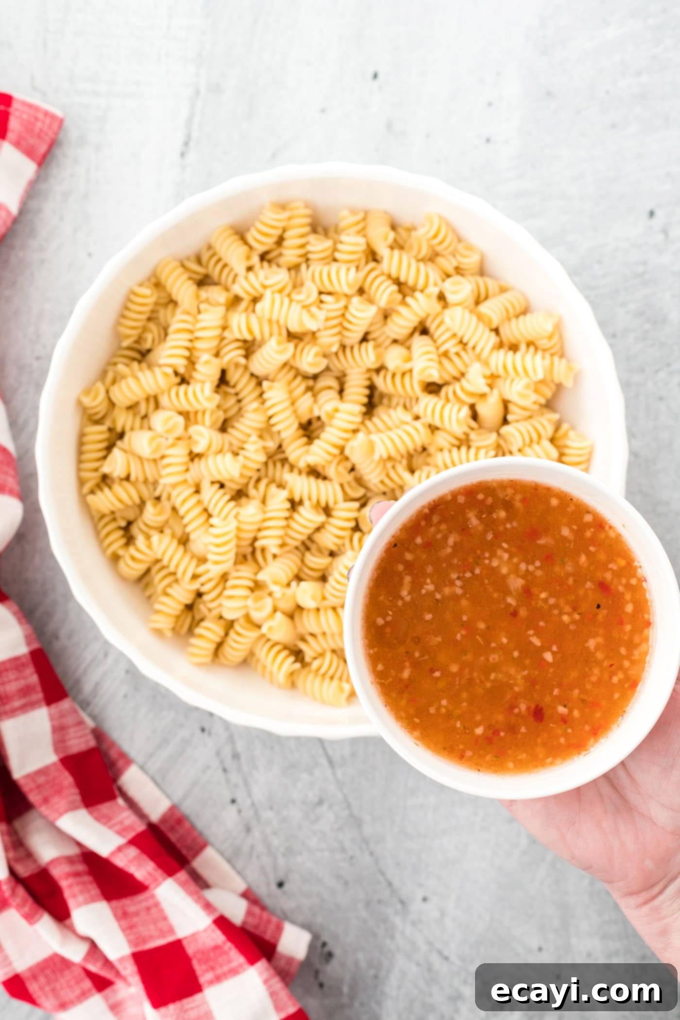 Zesty Italian Pasta Salad 7 Cooked pasta being tossed with Italian dressing in a bowl.