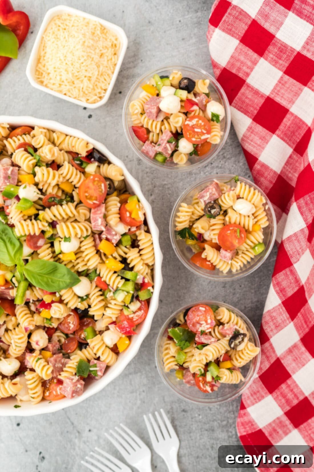 Zesty Italian Pasta Salad 9 A large bowl of Italian Pasta Salad with three smaller individual servings in cups beside it, perfect for a gathering.