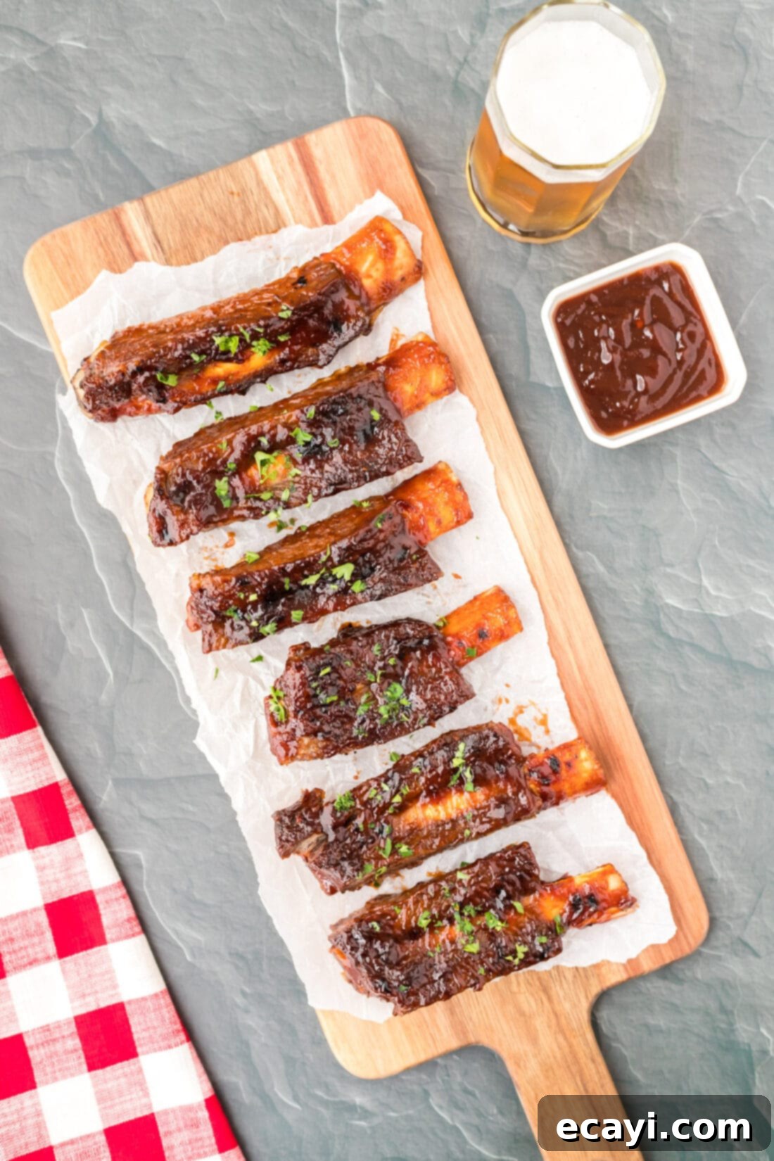Effortless Instant Pot Beef Ribs 7 Instant Pot Beef Ribs on a cutting board, drizzled with barbecue sauce, showcasing their tender texture.