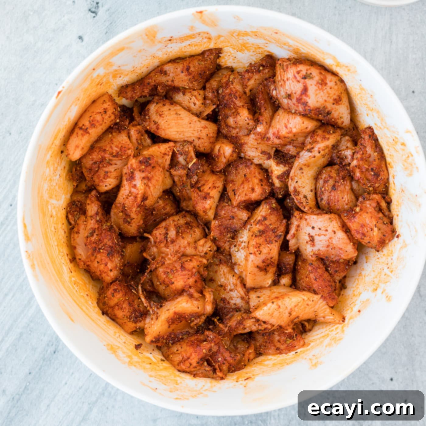 Spicy Cajun Chicken Pasta 5 Cajun seasoned chicken pieces in a bowl, coated with spices and olive oil.