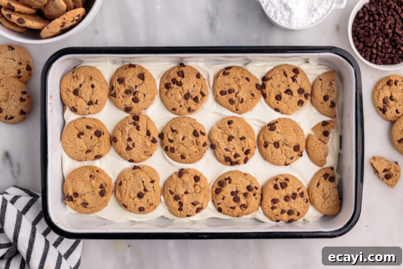 No-Bake Chocolate Chip Cookie Dream Cake 8 Multiple layers of chocolate chip cookies and cream cheese mixture visible inside a casserole dish, showing the cake in progress.