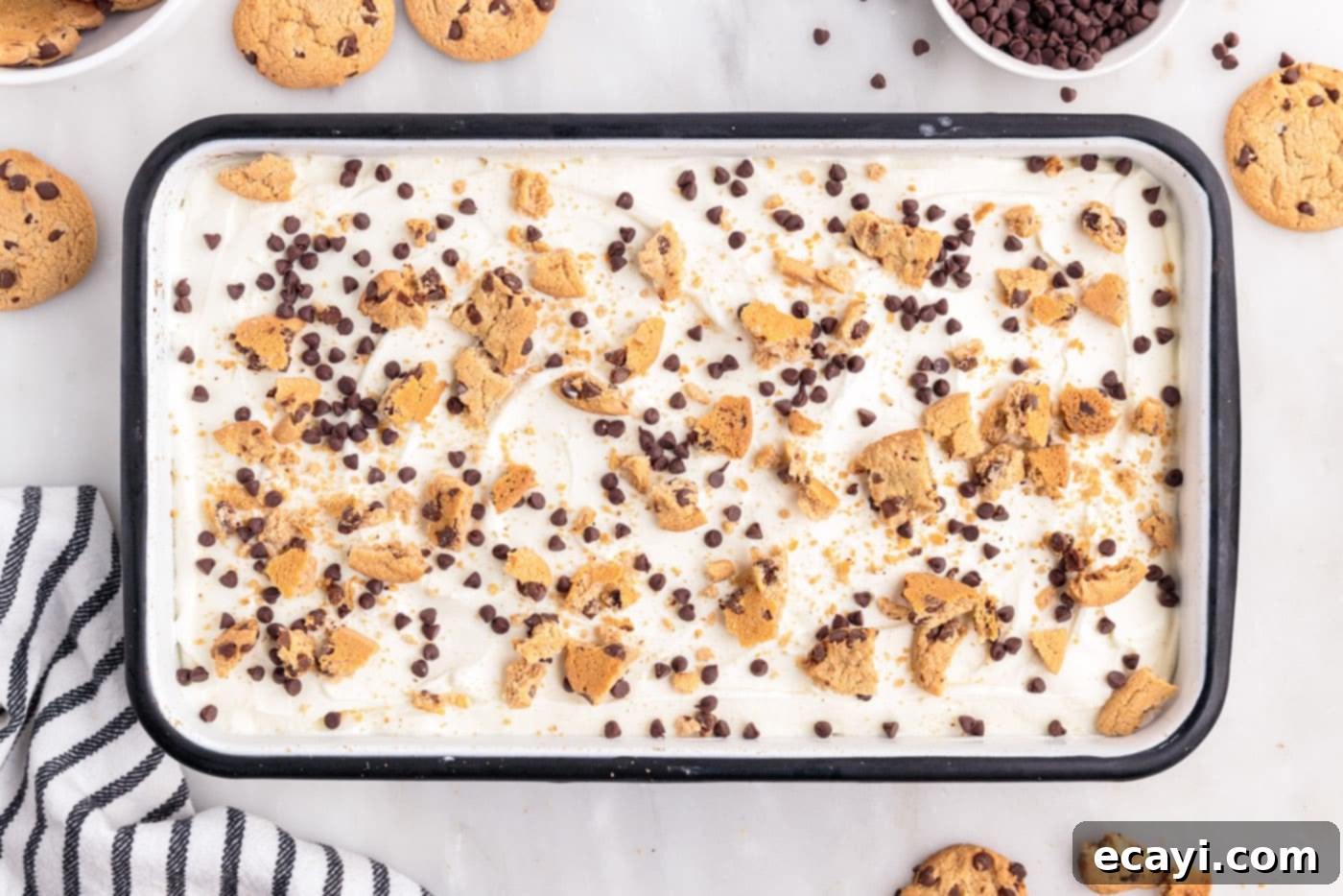 No-Bake Chocolate Chip Cookie Dream Cake 9 An overhead shot of the finished, un-decorated chocolate chip cookie icebox cake in a casserole dish, topped with the final cream layer.