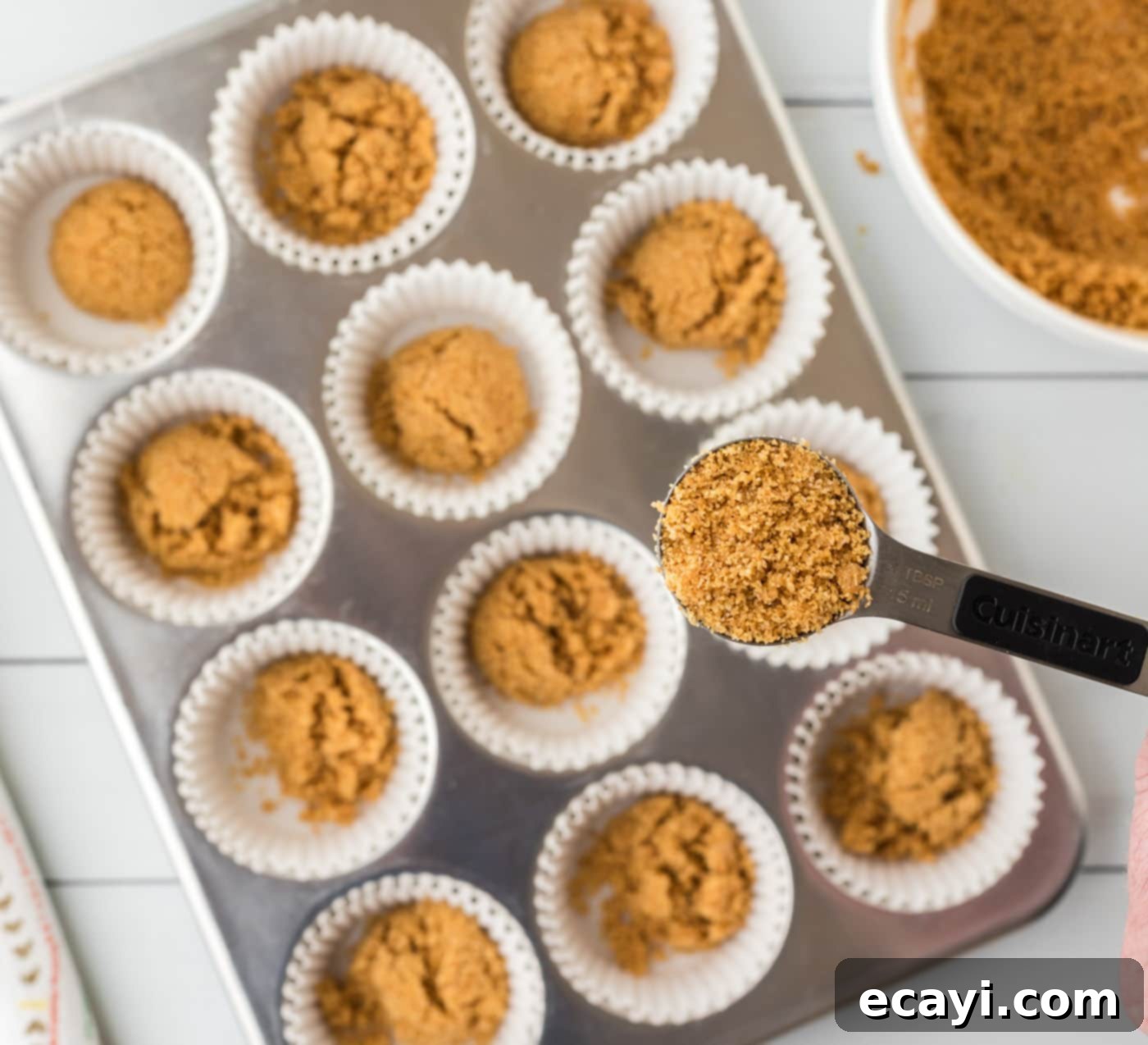 Key Lime Pie Bites 7 Graham cracker crust pressed into cupcake liners in a muffin tin, ready for baking.