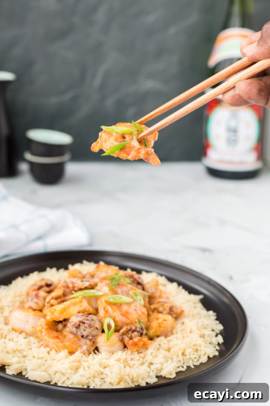 Candied Honey Walnut Shrimp 2 chopsticks lifting Honey Walnut Shrimp, showcasing its crispy texture and glossy sauce with candied walnuts