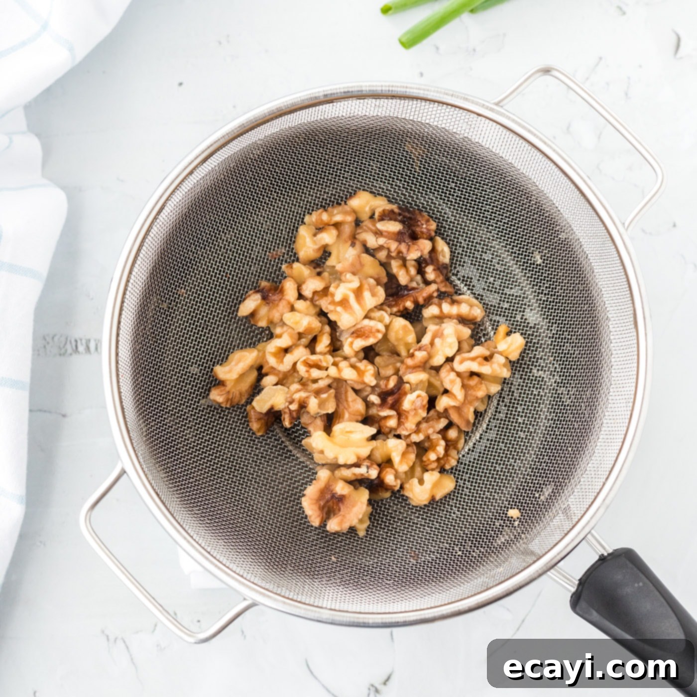 Candied Honey Walnut Shrimp 6 Candied walnuts being removed from a saucepan after boiling, ready to be drained