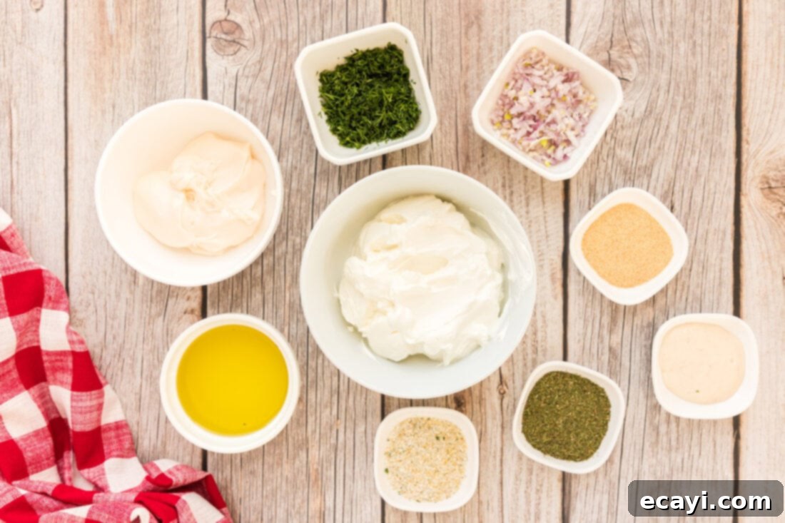 Creamy Dill Dream 4 All the fresh and dry ingredients for dill dip laid out on a clean surface, including sour cream, mayo, dill, and spices.