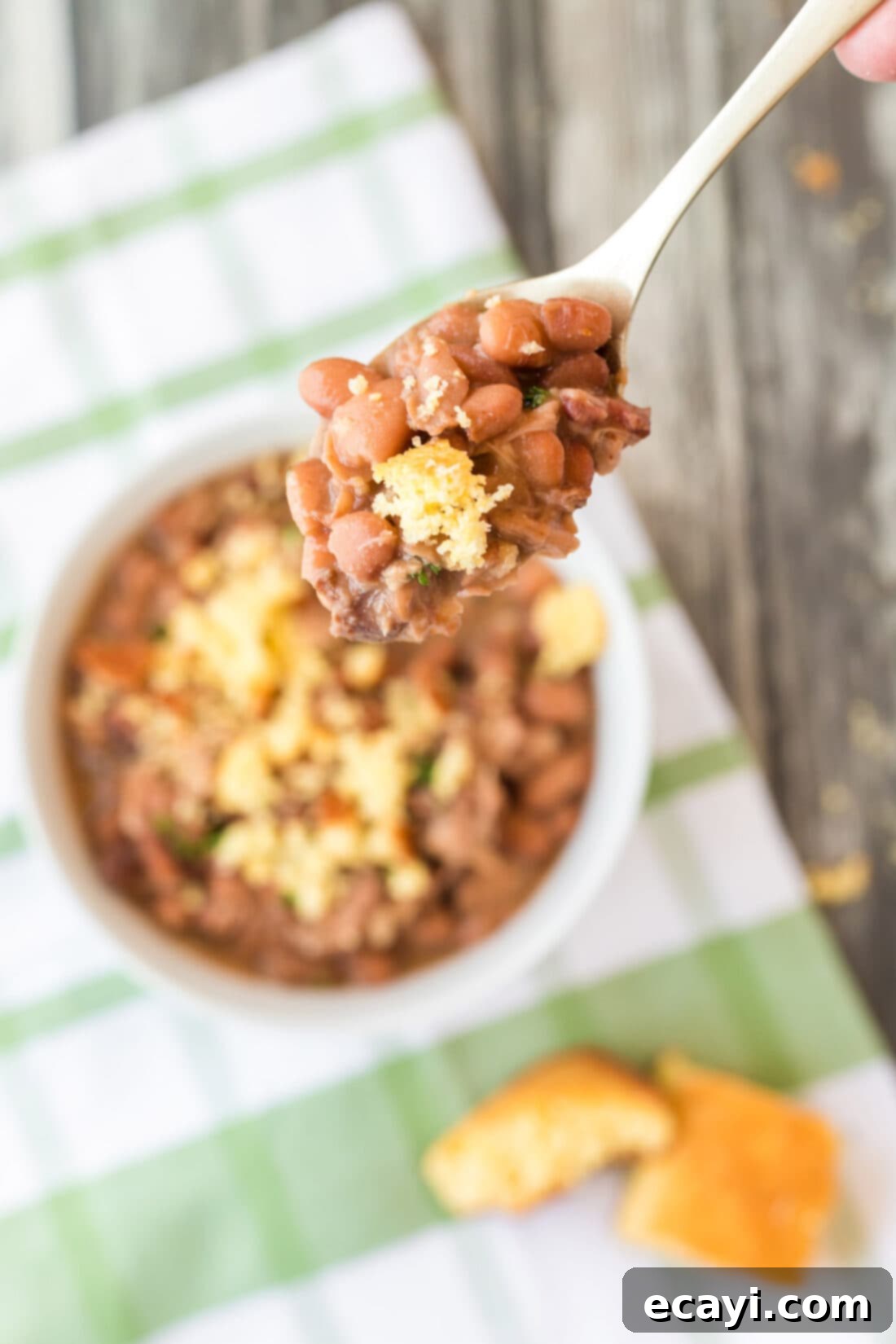 Effortless Slow Cooker Pinto Beans 11 A spoonful of Slow Cooker Pinto Beans with a side of cornbread, ready to be served