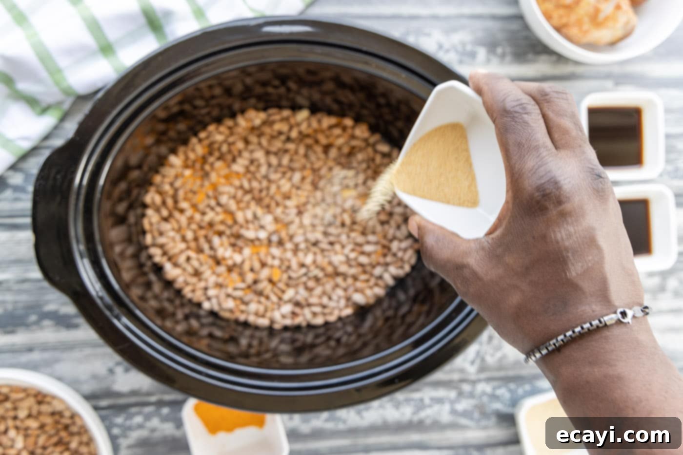 Effortless Slow Cooker Pinto Beans 6 Pouring a generous amount of seasoning over the first layer of pinto beans in a crockpot