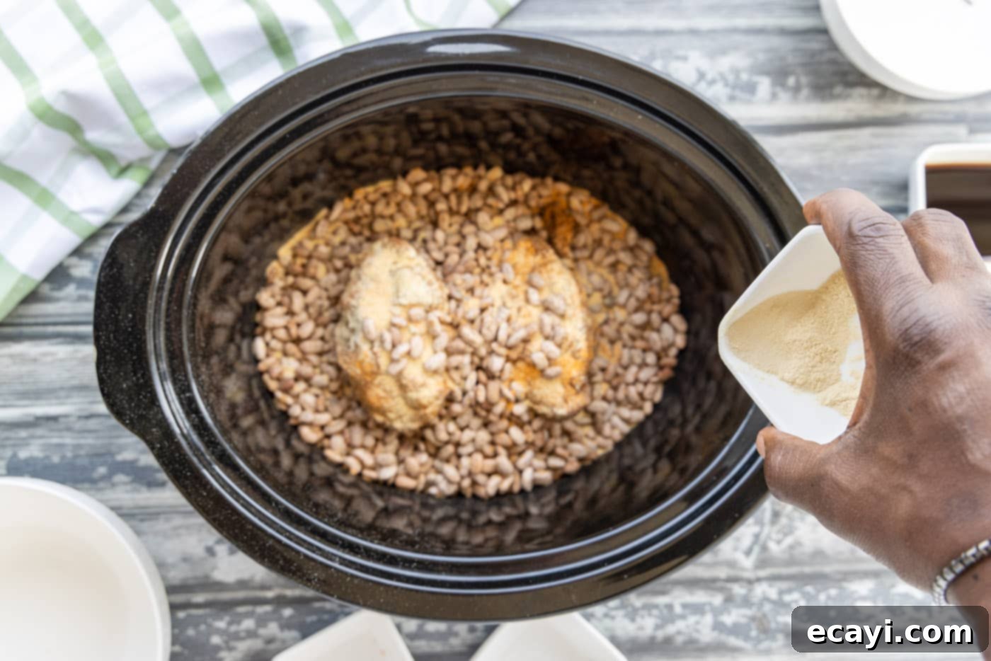 Effortless Slow Cooker Pinto Beans 9 Adding the final layer of pinto beans over the turkey tails and previous seasoning
