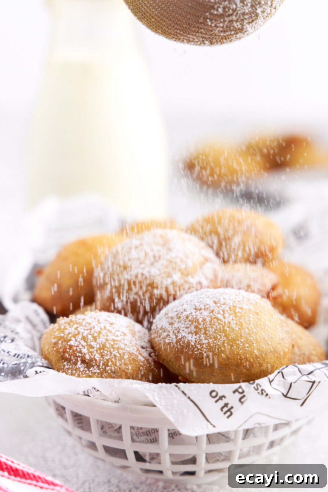 Deep-Fried Oreo Delight 3 Close-up shot of a hand dusting freshly fried Oreos with a cloud of powdered sugar.