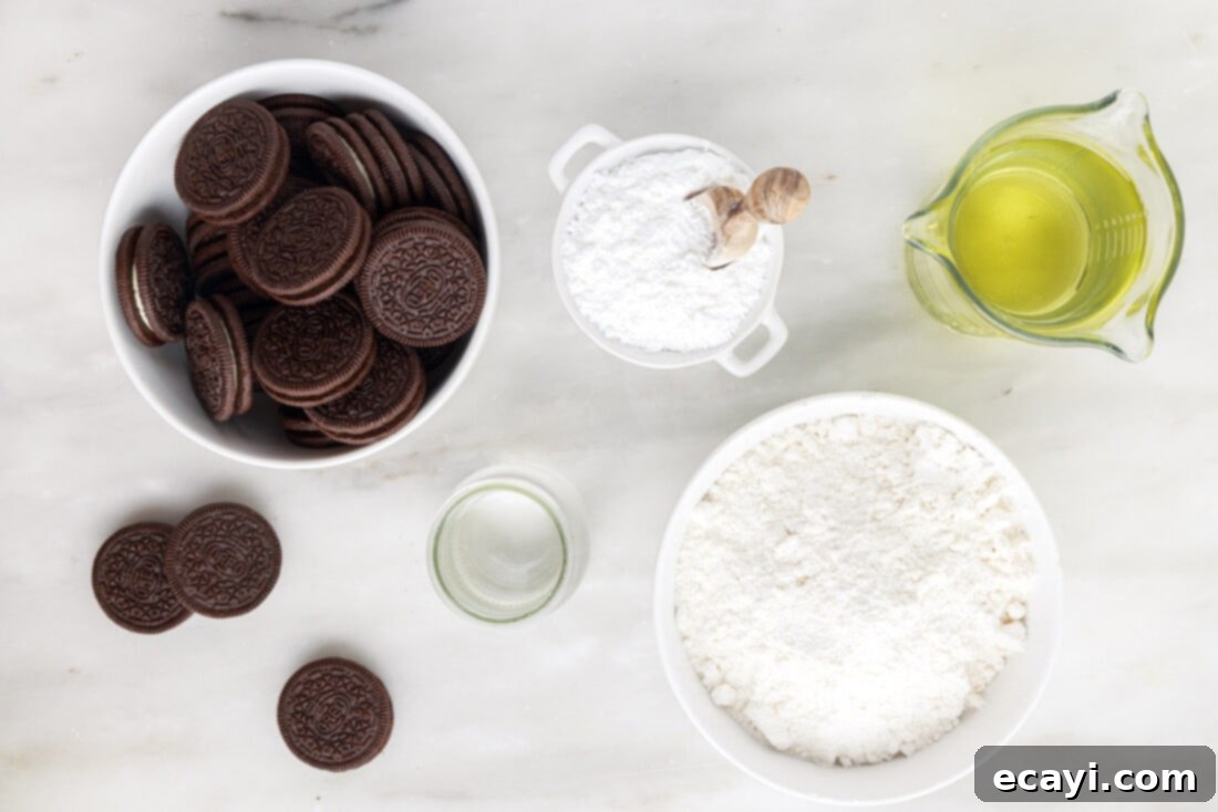 Deep-Fried Oreo Delight 4 Ingredients laid out on a table: a package of Oreos, a bowl of pancake mix, a jug of water, and a bottle of vegetable oil, all ready for making fried Oreos.