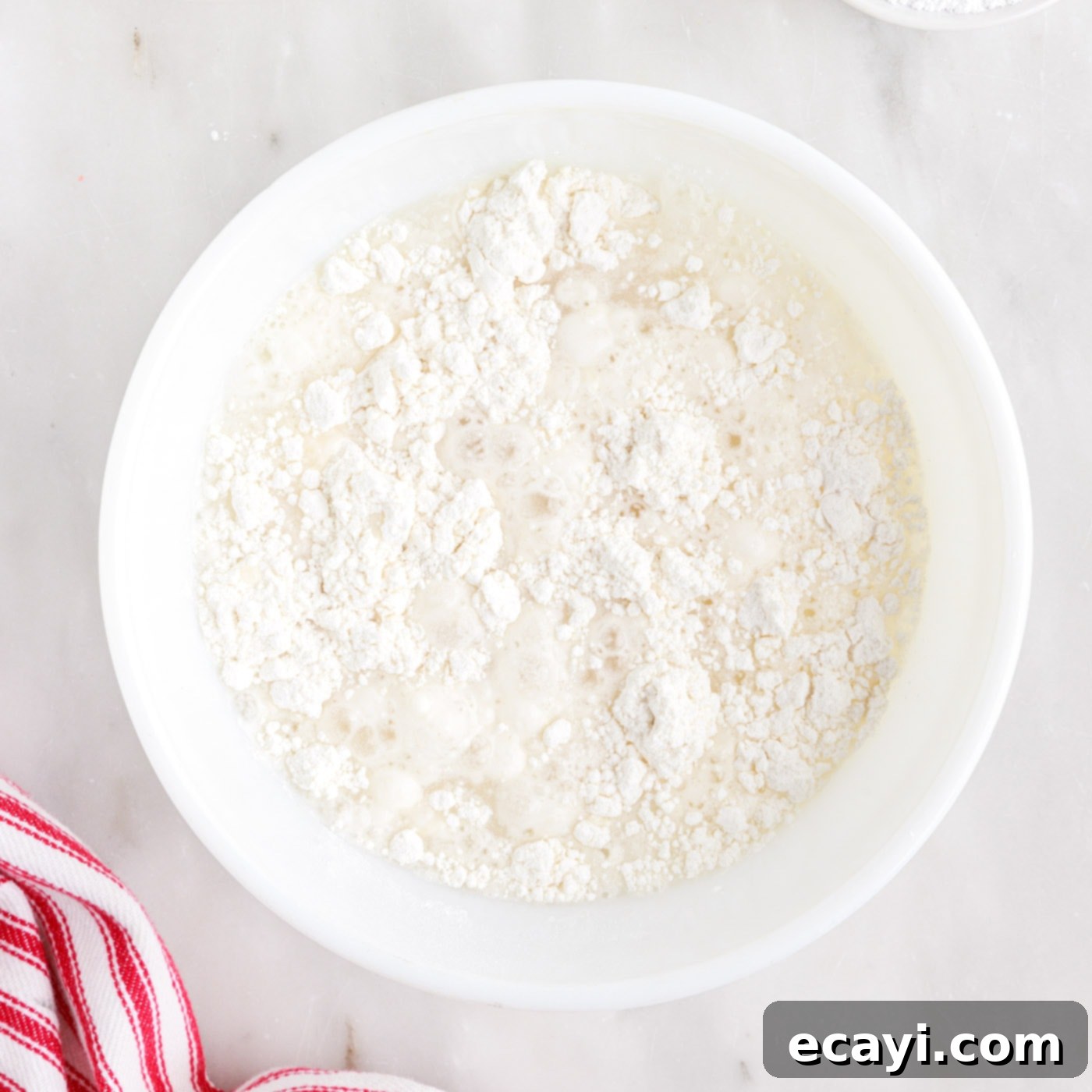 Deep-Fried Oreo Delight 5 Pancake mix being whisked with water in a white bowl to create a smooth batter.