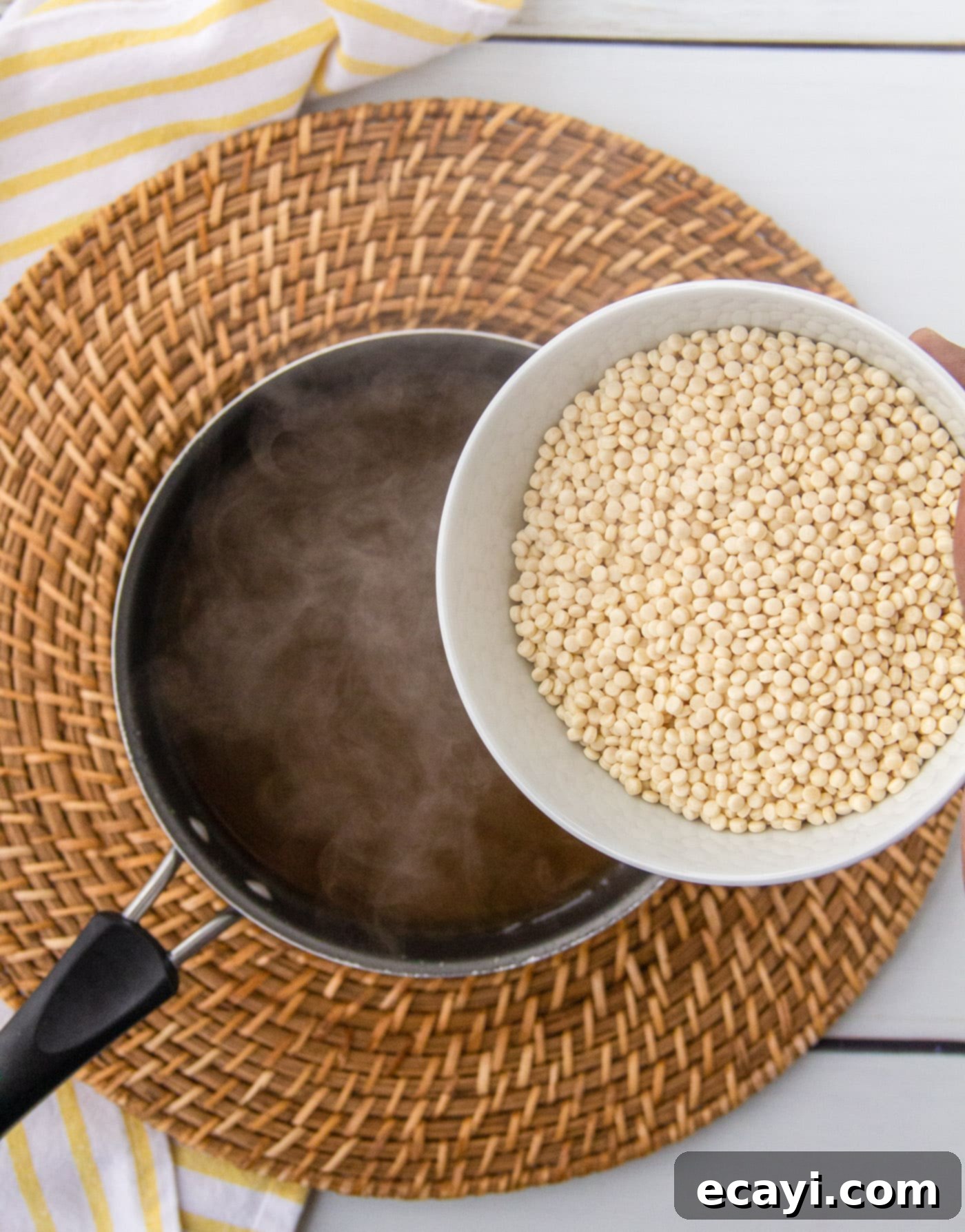 Bright Lemon Couscous 6 Pouring pearl couscous into boiling vegetable broth in a saucepan