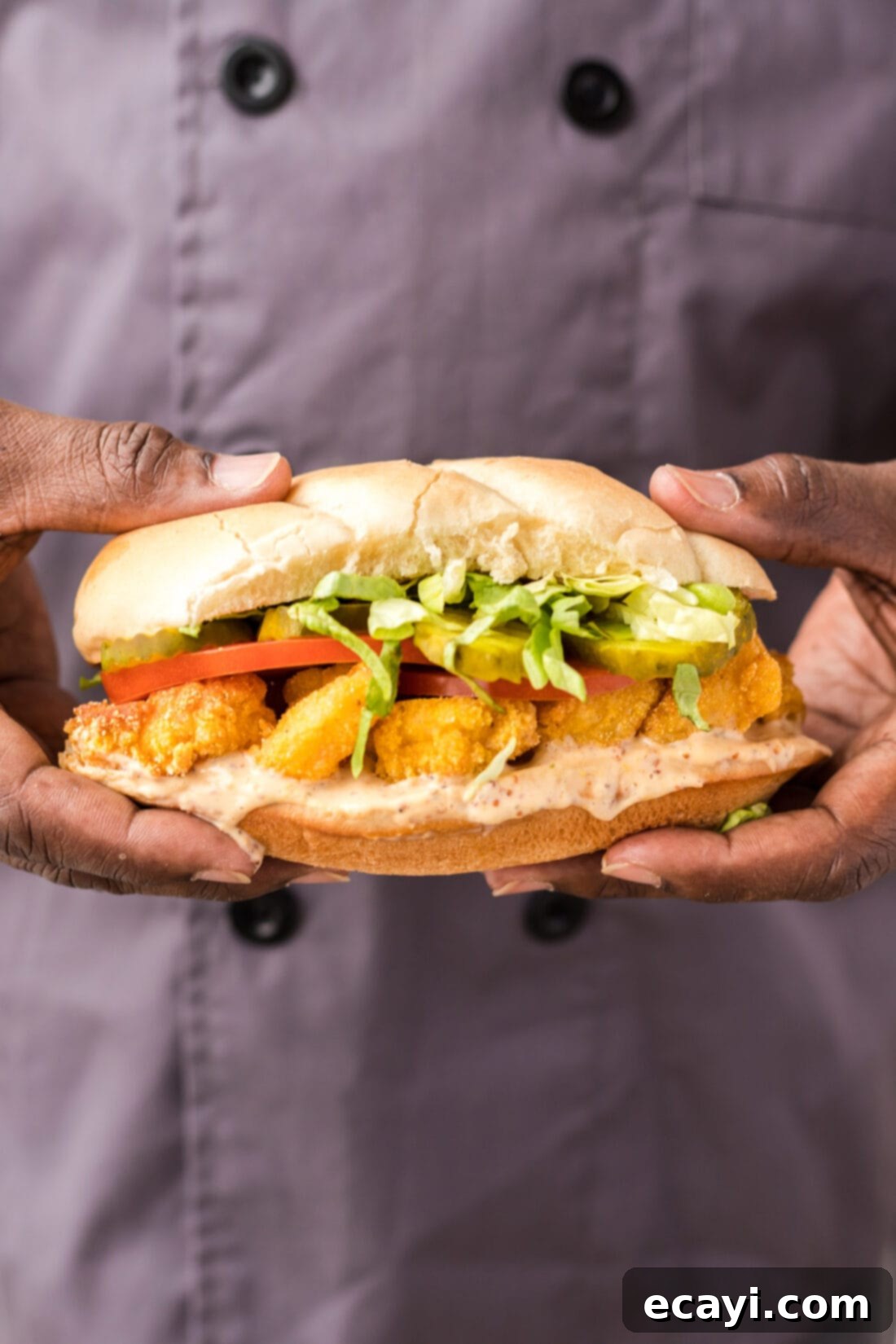 Crispy Golden Shrimp Po' Boy 2 A chef holding a freshly made, mouth-watering Shrimp Po Boy sandwich, showcasing its crispy fried shrimp and fresh fillings.
