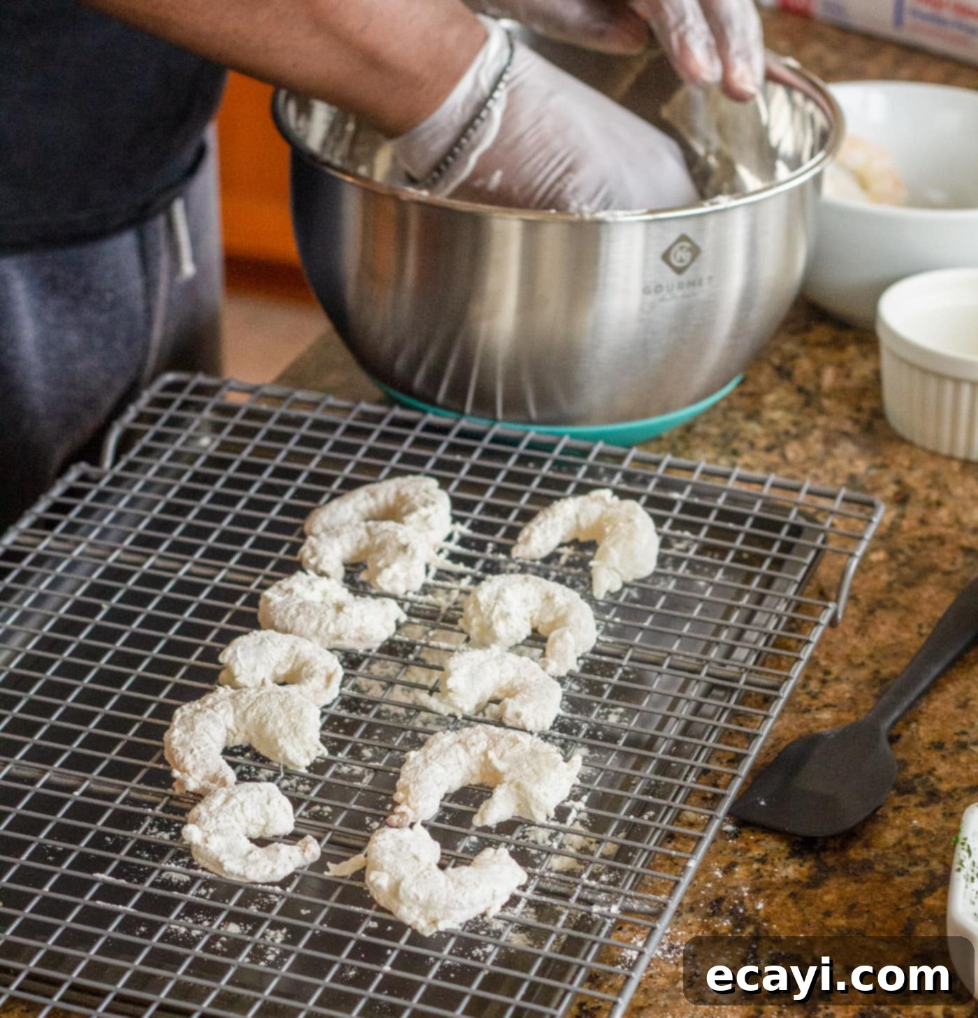 Crispy Golden Shrimp Po' Boy 5 Shrimp evenly coated in flour mixture resting on a wire rack, ready for the next breading step.