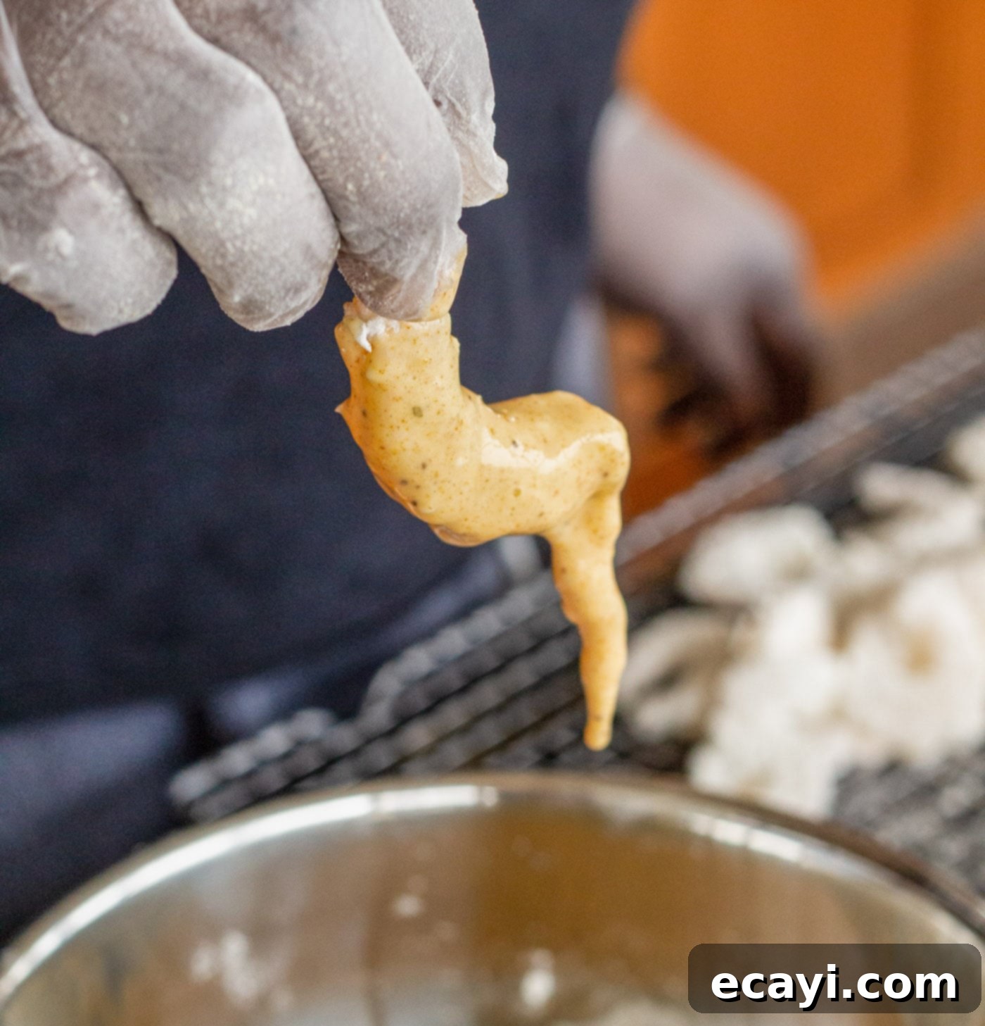 Crispy Golden Shrimp Po' Boy 9 A shrimp being dipped into the seasoned egg and milk mixture after its initial flour dredge.