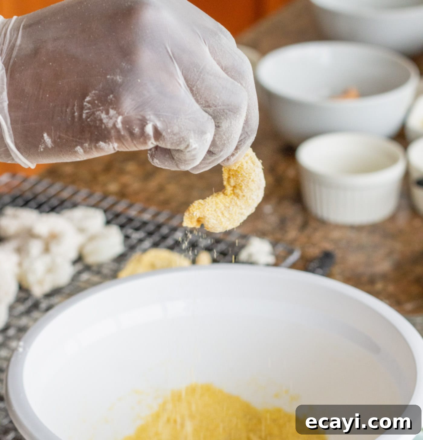 Crispy Golden Shrimp Po' Boy 10 A wet-dredged shrimp being coated in the yellow cornmeal mixture, ensuring full coverage.
