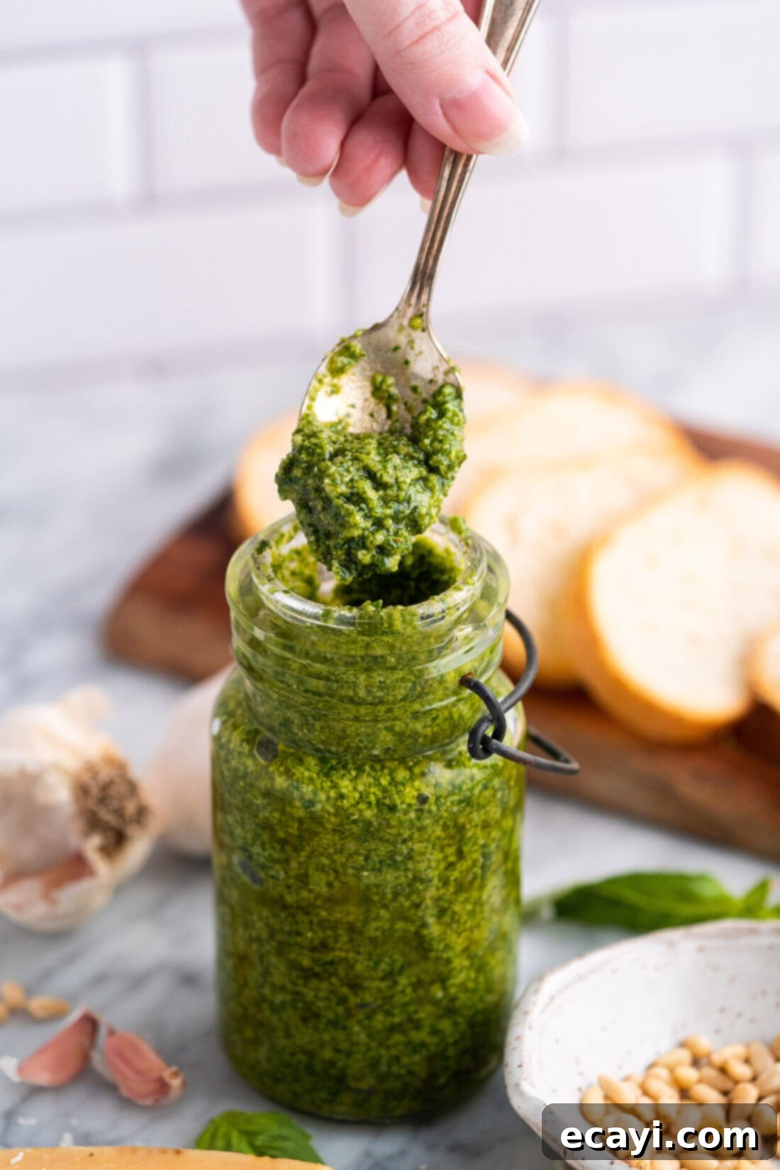 Pesto Perfection 3 Fresh homemade basil pesto stored in a clear glass jar, with a thin layer of olive oil on top to preserve its vibrant green color.