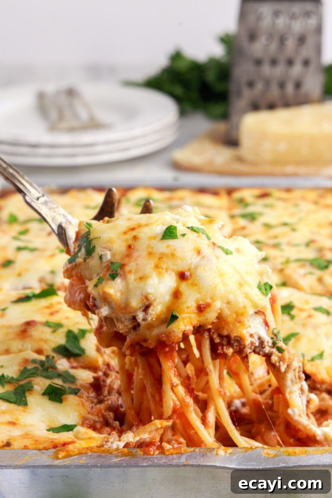 The Ultimate Million Dollar Spaghetti 2 Lifting a generous portion of Million Dollar Spaghetti with a pasta fork, showcasing its creamy layers and golden-brown cheesy top.