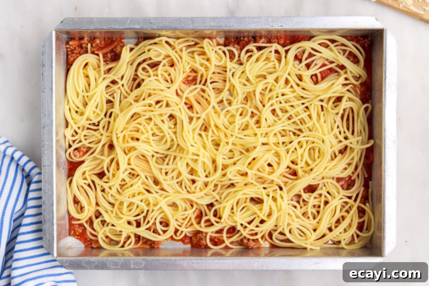 The Ultimate Million Dollar Spaghetti 11 Layer of spaghetti noodles placed over the meat sauce in a baking pan.