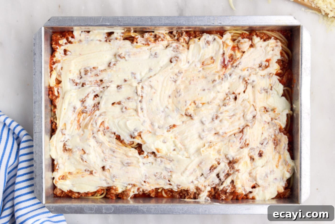 The Ultimate Million Dollar Spaghetti 13 Creamy ricotta cheese mixture dolloped over the meat sauce and spaghetti layers in the baking dish.