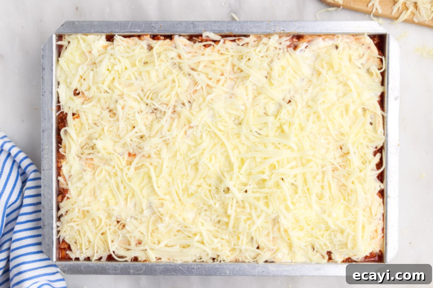 The Ultimate Million Dollar Spaghetti 14 A generous layer of parmesan cheese sprinkled over mozzarella, meat sauce, ricotta, and noodles, ready for baking.