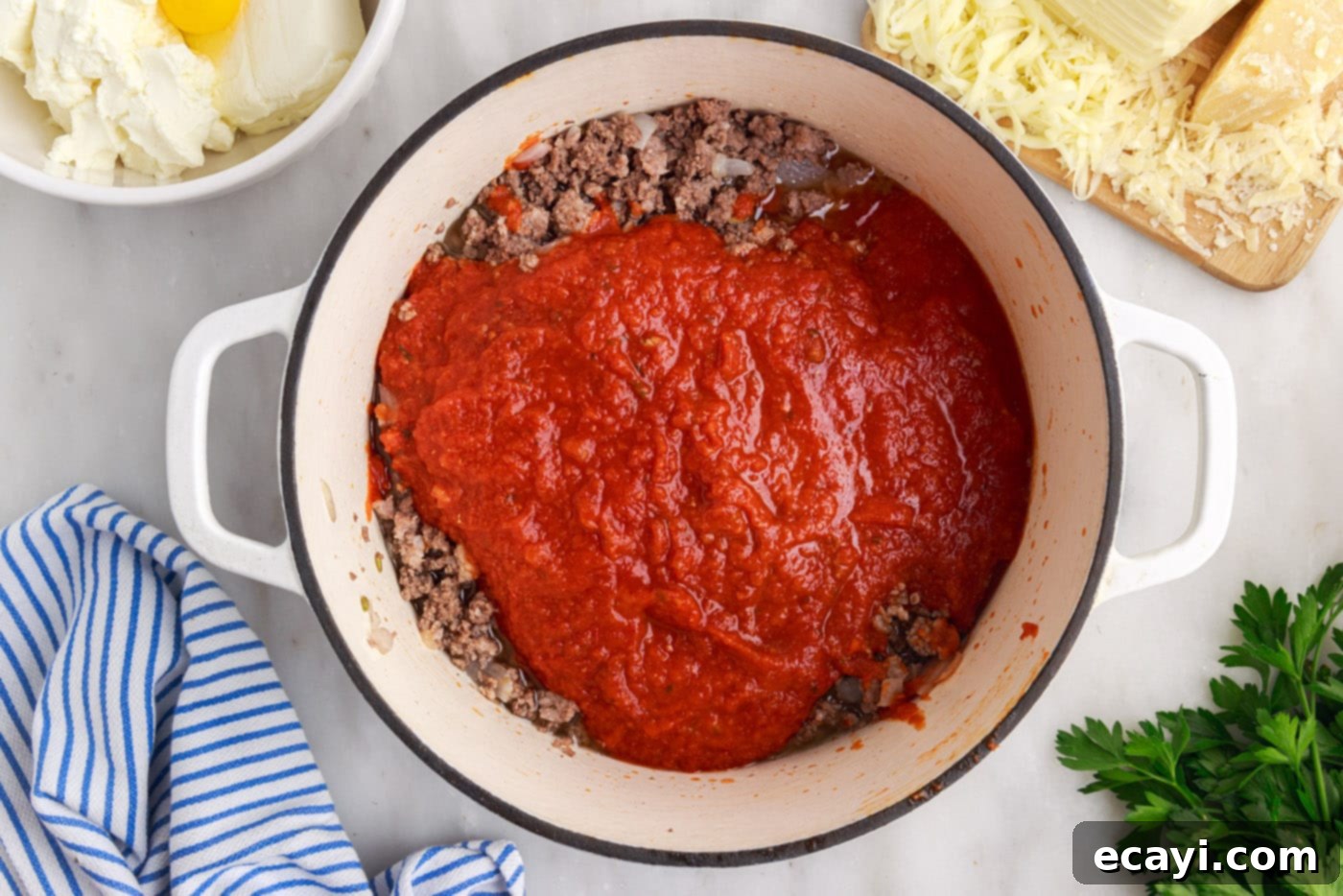 The Ultimate Million Dollar Spaghetti 7 Marinara sauce being stirred into the cooked ground beef and sausage mixture in a skillet.