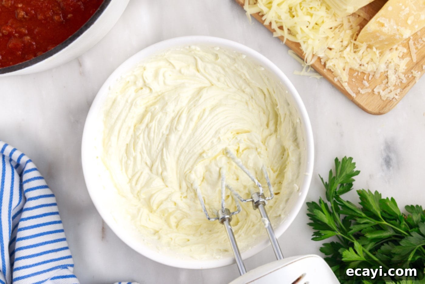 The Ultimate Million Dollar Spaghetti 9 A hand mixer blending the ricotta, cream cheese, and egg into a smooth, creamy mixture.