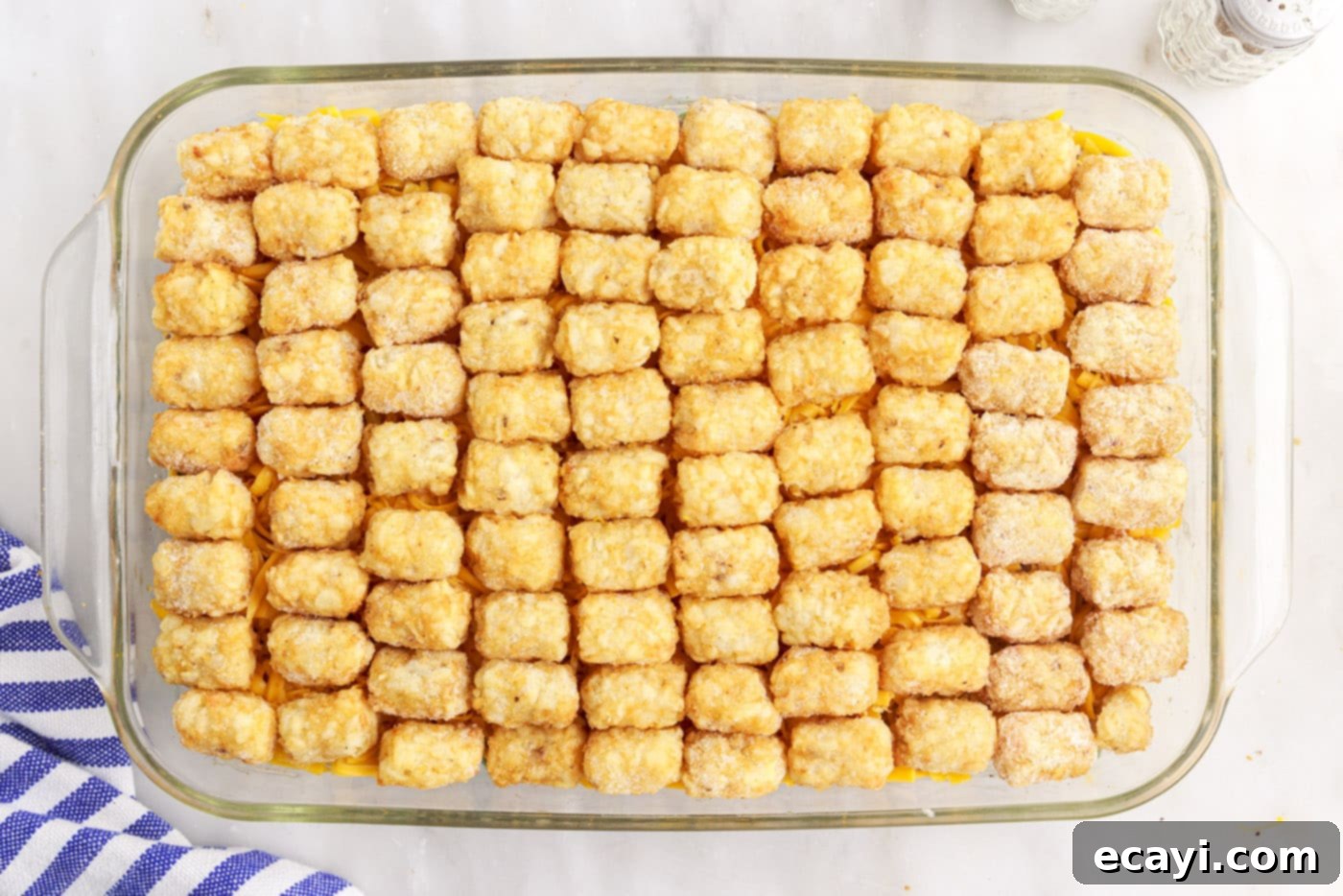 Crispy Tatertot Bake 11 Frozen tater tots arranged on top of the cheese layer in the casserole dish