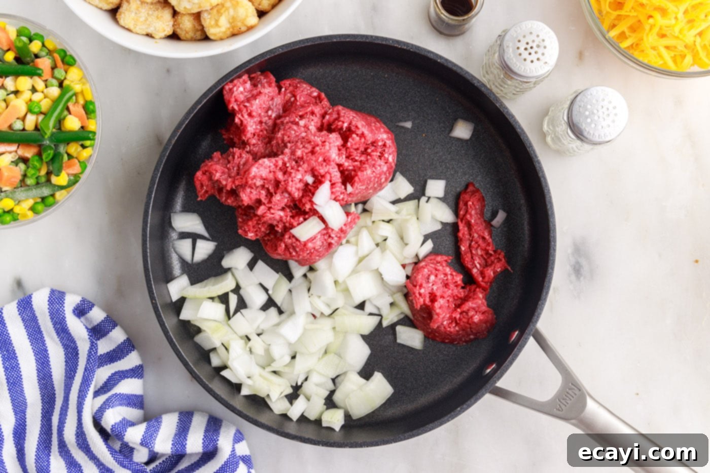 Crispy Tatertot Bake 5 Ground beef and diced onion cooking in a large skillet