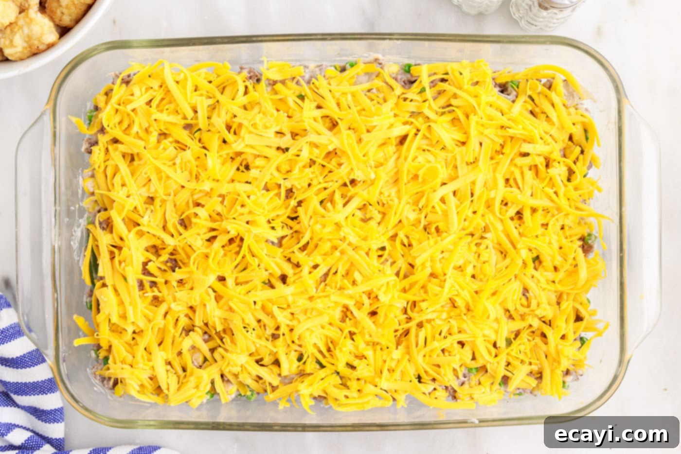 Crispy Tatertot Bake 10 Shredded cheddar cheese layered over the beef mixture in the casserole dish