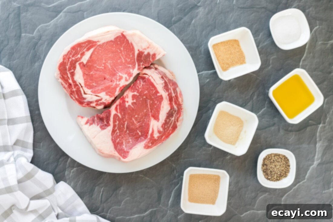 Flawless Reverse Sear Ribeye 4 Ingredients for Reverse Sear Ribeye laid out on a board: ribeye steaks, olive oil, and a blend of spices.