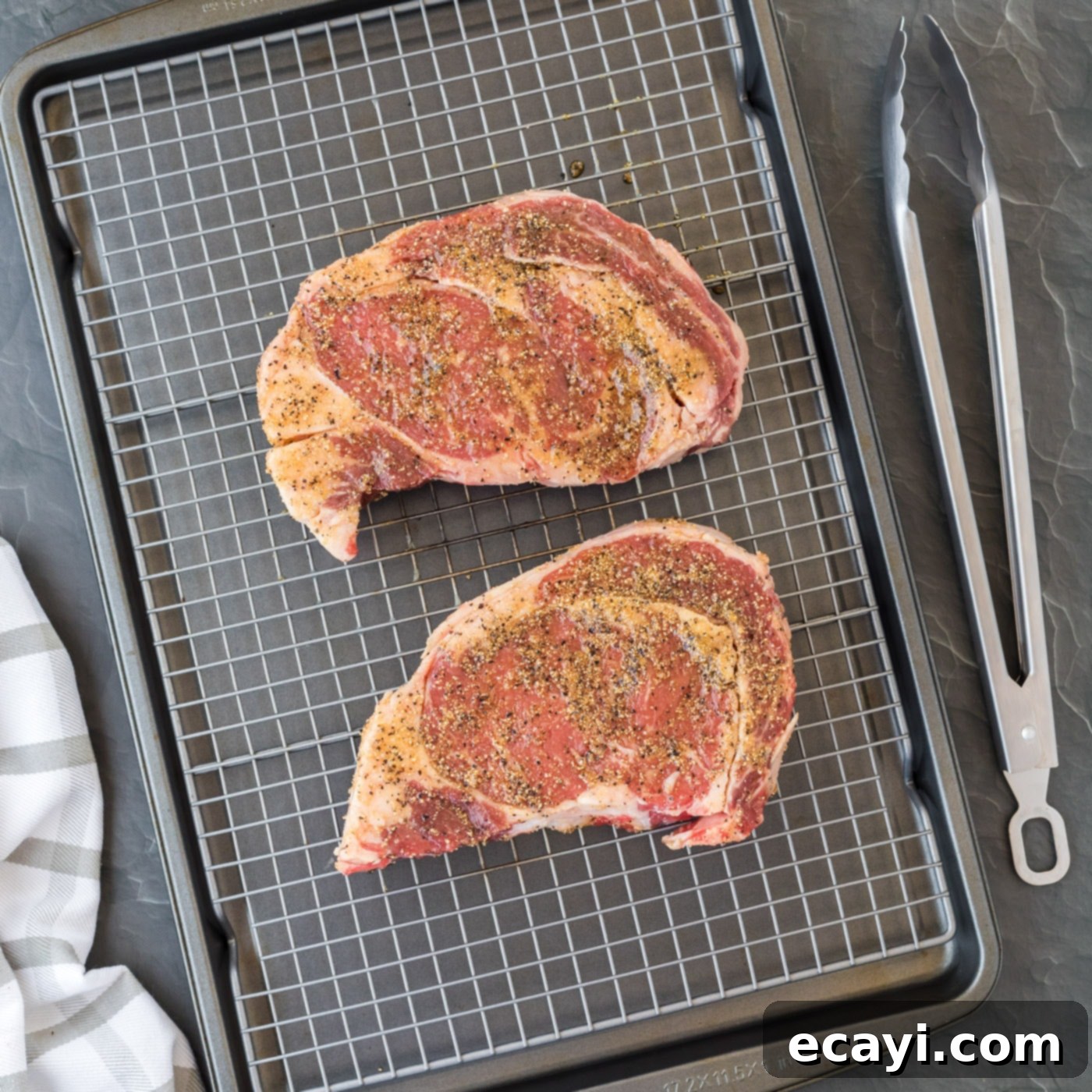 Flawless Reverse Sear Ribeye 6 Ribeye steak rubbed with spices, placed on a wire rack over a baking sheet.