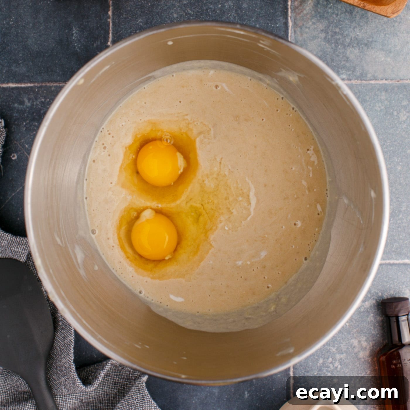 Golden Banana Muffins 7 adding eggs to banana muffin batter in a mixing bowl