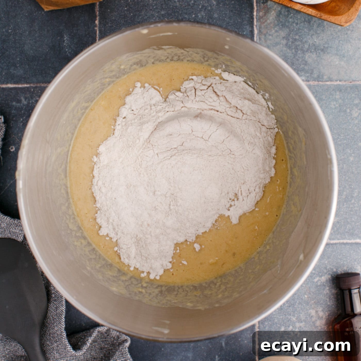 Golden Banana Muffins 8 adding dry ingredients to wet ingredients for banana muffins in a bowl