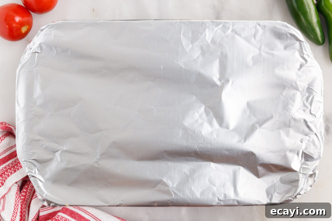 Crunchy Chili Cheese Delight 11 A casserole dish covered with aluminum foil, prepared for baking in the oven.